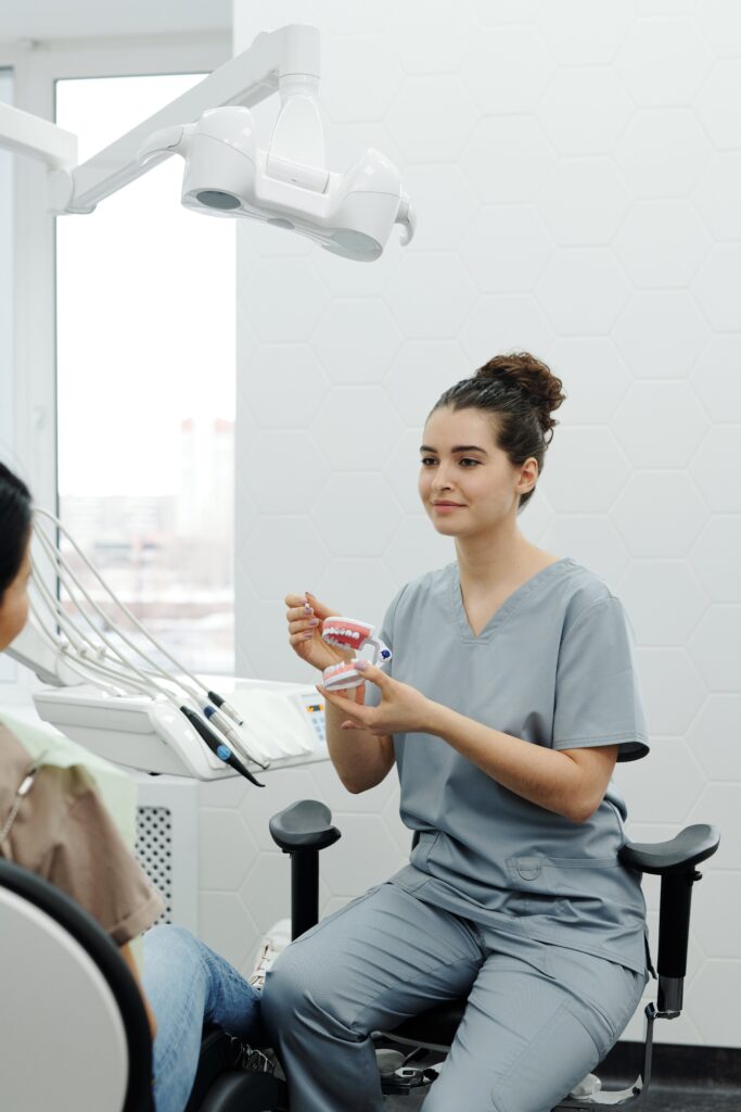 Dental Hygiene Apprentice holding a model to demonstrate how to clean the teeth